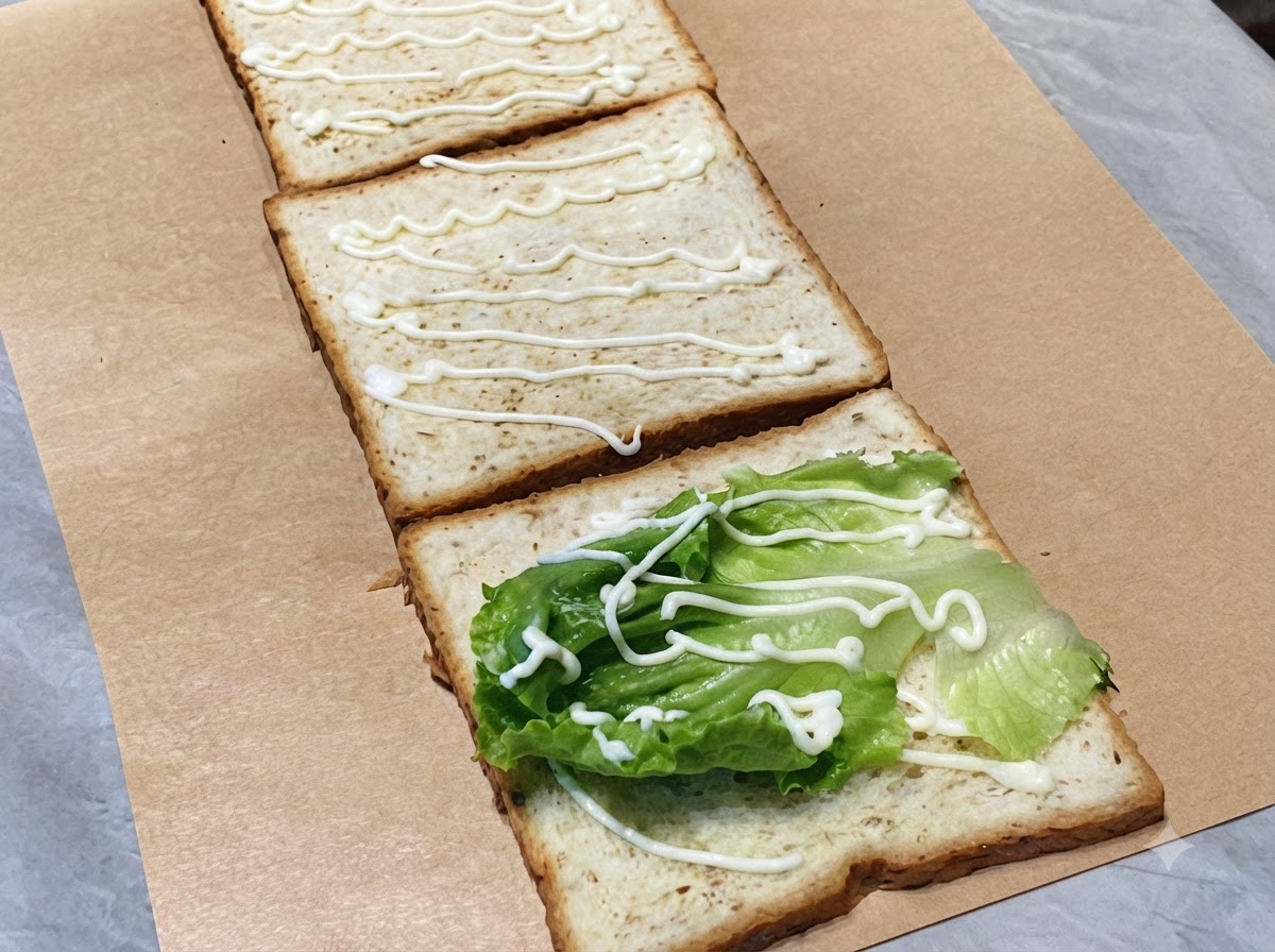 Fette di cetriolo verde fresco disposte sulla seconda fetta di pane con un filo di maionese.