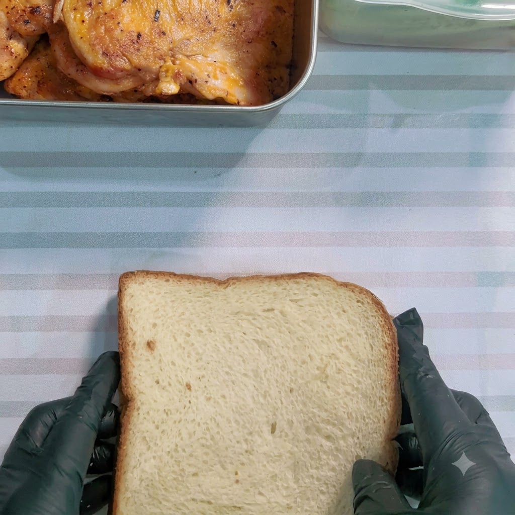Un coltello seghettato che taglia diagonalmente un panino avvolto su una superficie a righe.