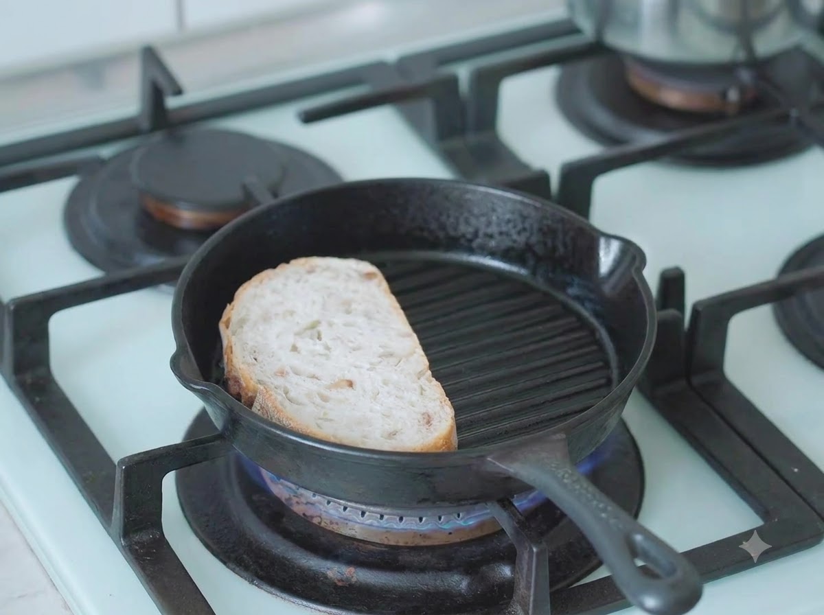 Una fette di pane cafone che si tosta in una padella di ghisa calda sul fuoco.
