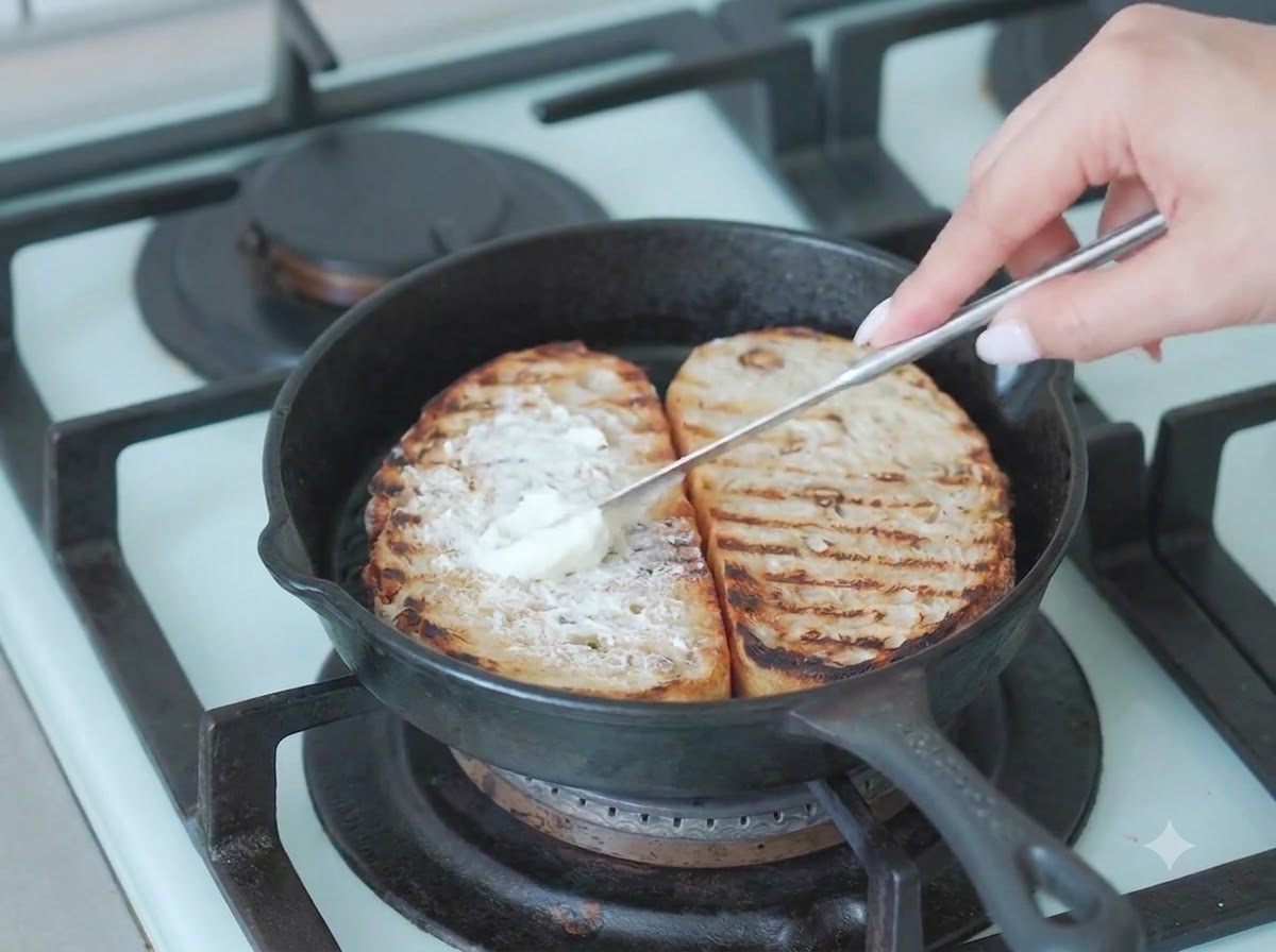 Foglie di rucola fresca verde posizionate sopra lo strato di formaggio spalmabile sul pane cafone.