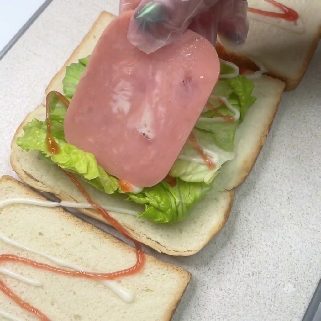 Una fetta di prosciutto posizionata sopra uno strato di lattuga su una fetta di pane con condimenti.