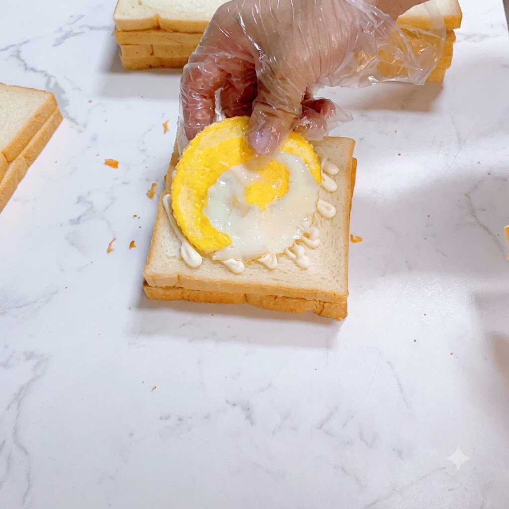 Un uovo fritto posizionato con cura sopra il pane bianco spalmato di maionese.