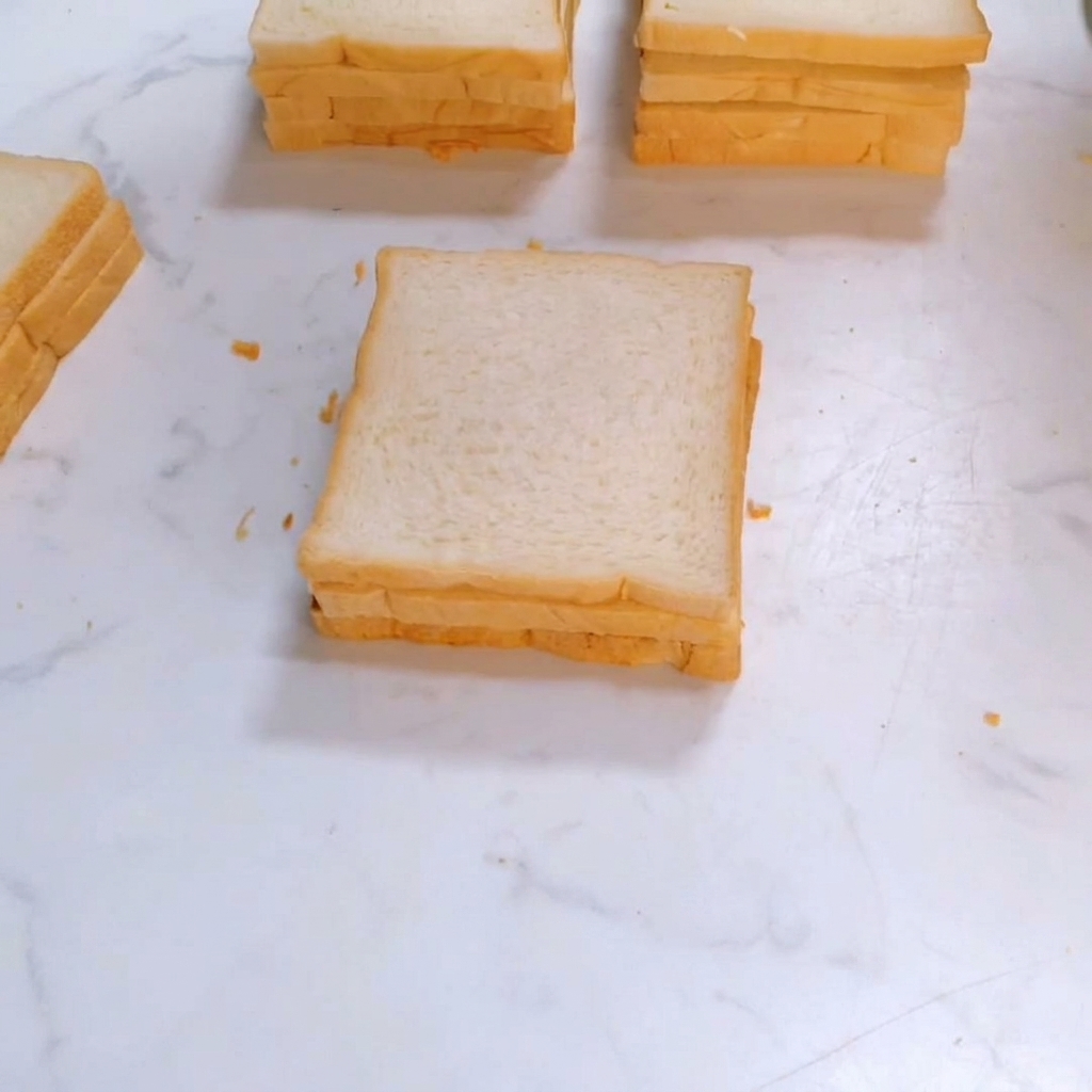 Una terza fetta di pane bianco quadrato posizionata sopra la pila del panino.