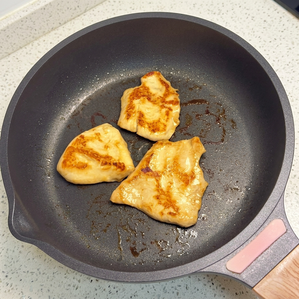 Pezzi di pollo in cottura in una padella fino a doratura.