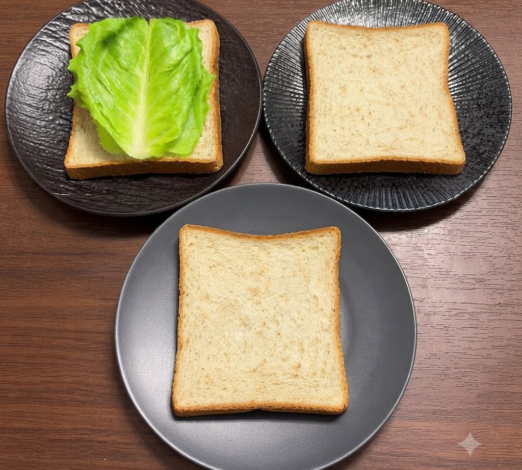 Foglie di insalata verde fresca disposte ordinatamente sopra fette di pane integrale su piatti neri.