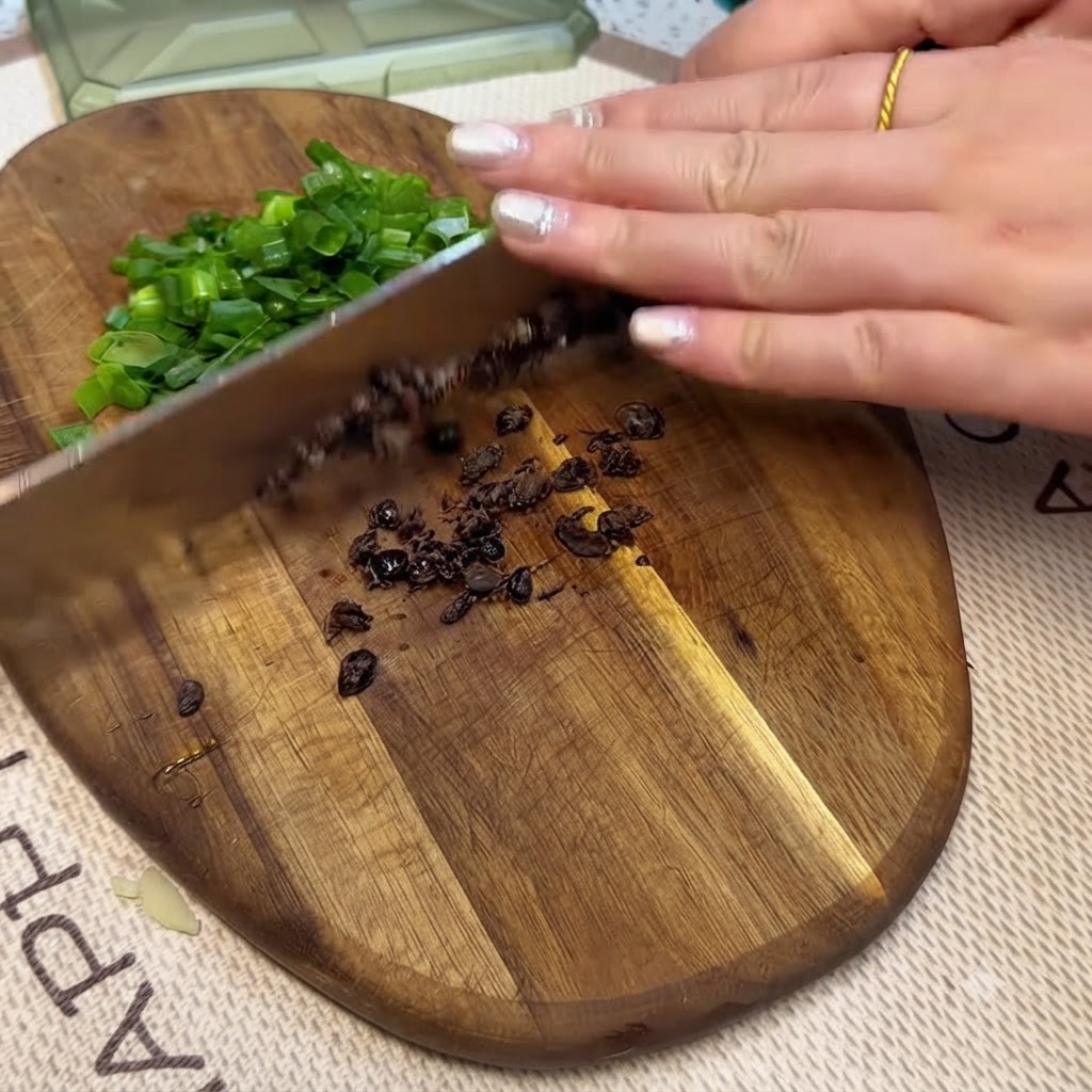 Fagioli neri fermentati e cipollotti tritati tagliati finemente su un tagliere di legno con un coltello.