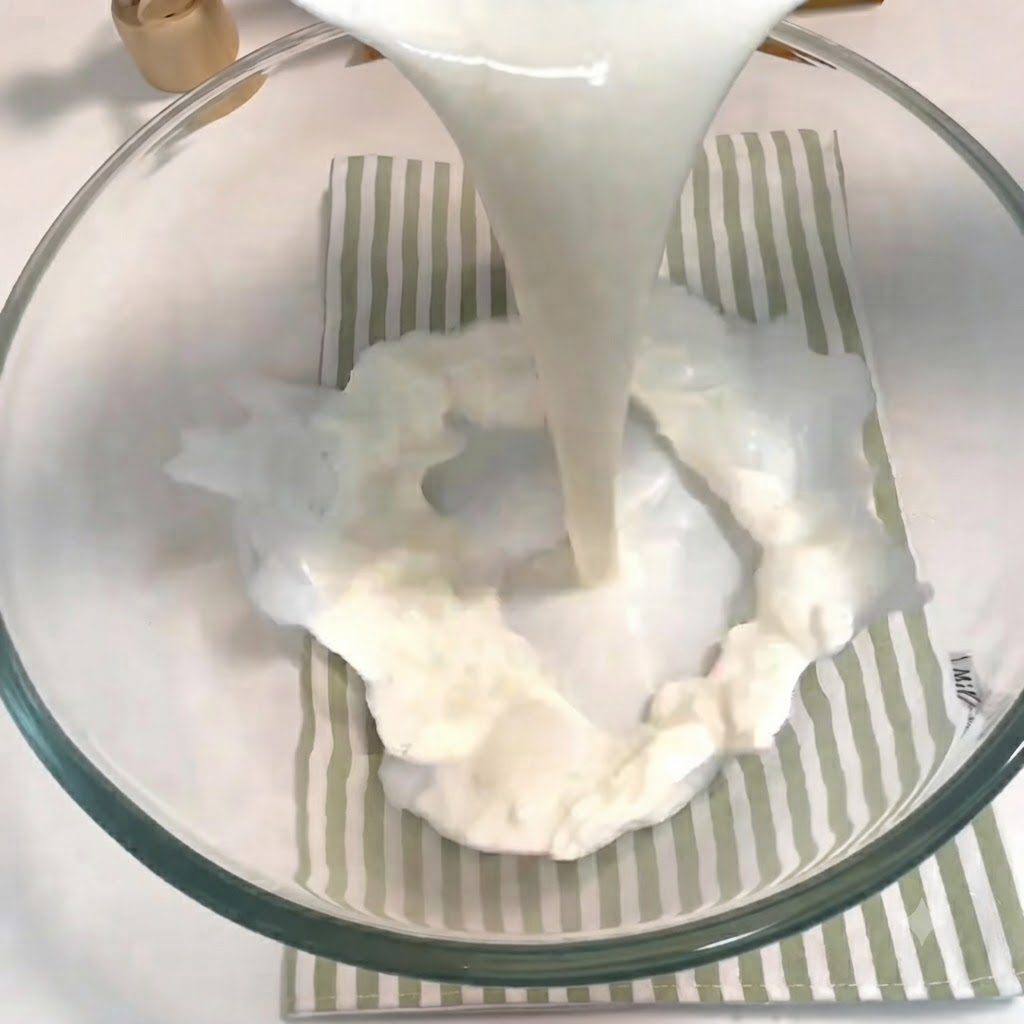 Latte, zucchero, lievito e un uovo versati e sbattuti insieme in una ciotola di vetro.