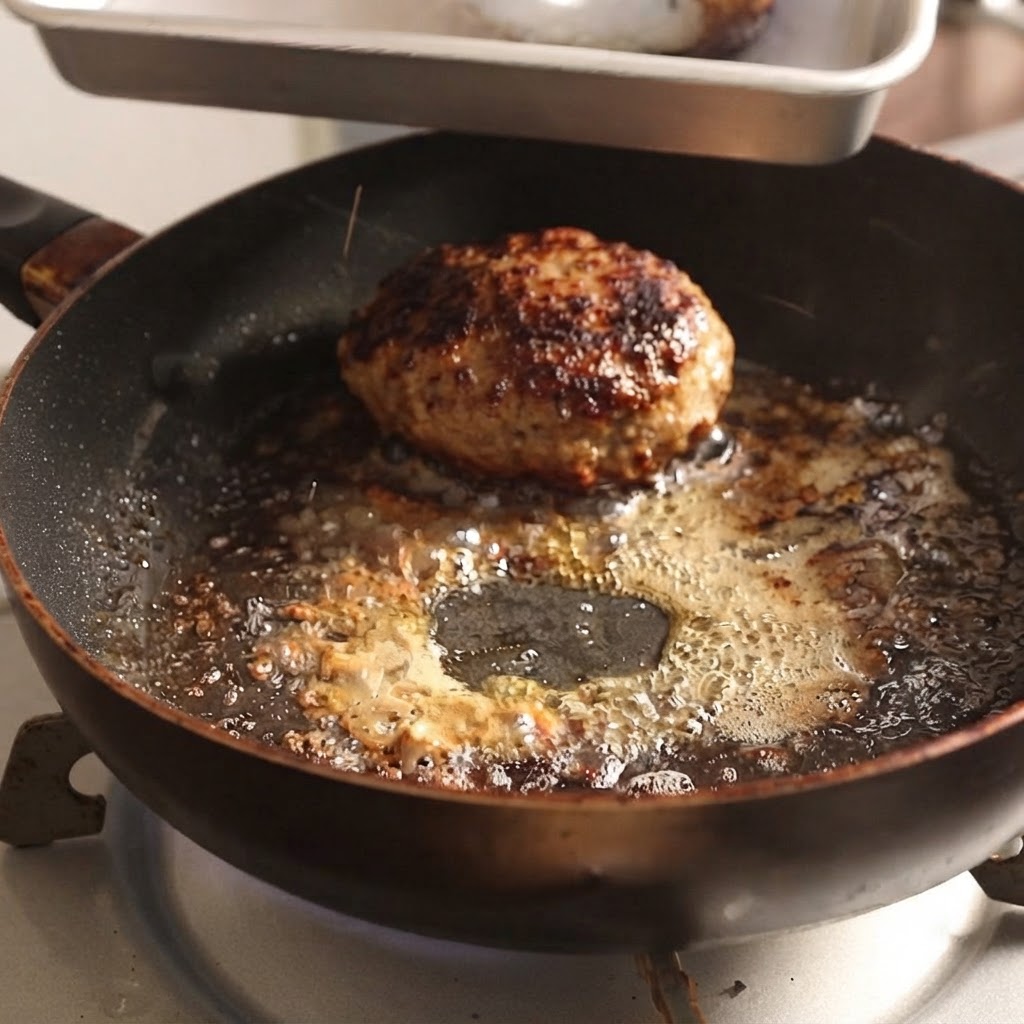 Hamburger prelevati da una padella calda utilizzando pinze di metallo.