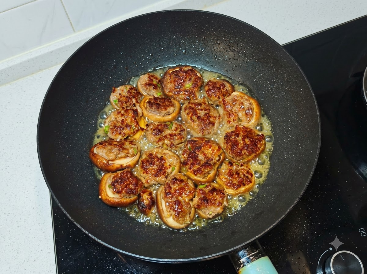 Acqua versata nel wok attorno ai funghi ripieni di carne saltati in padella.