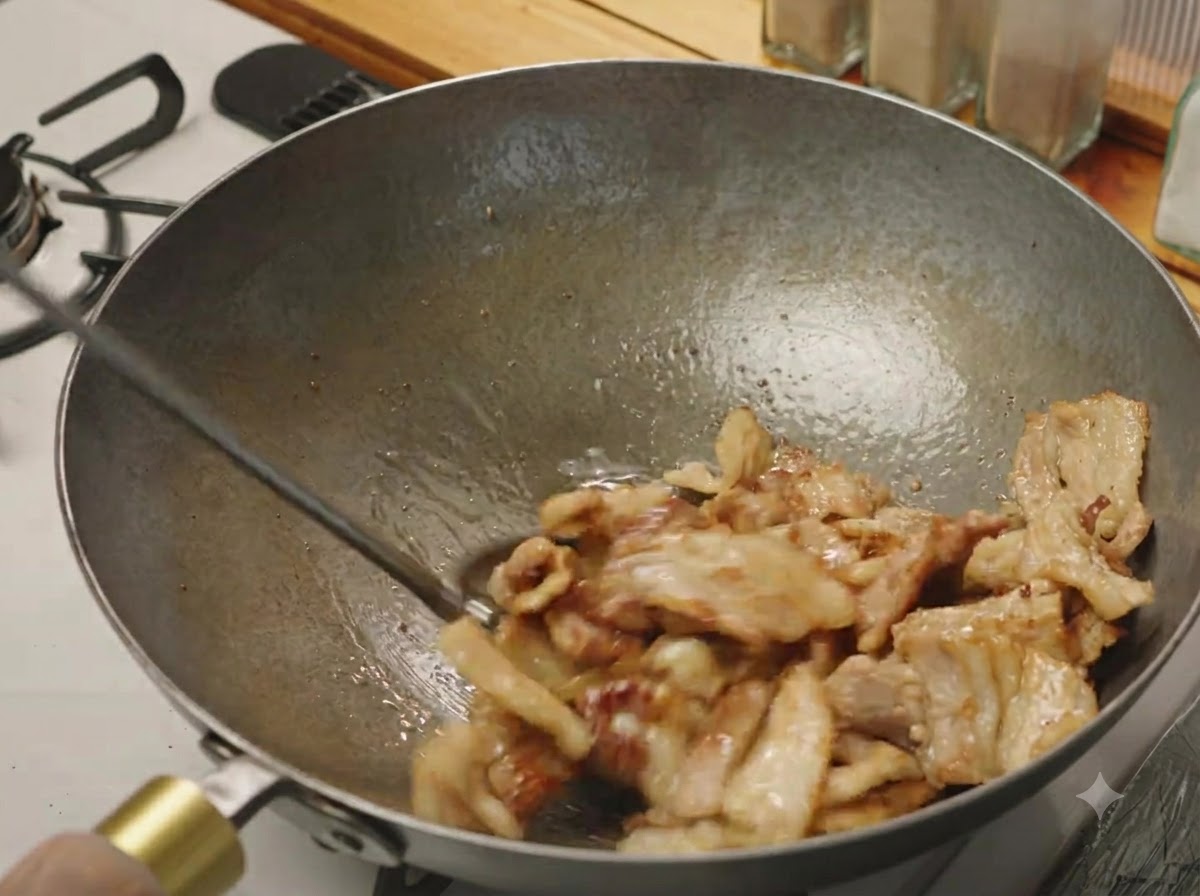 Fette di pancetta di maiale saltate in un wok fino a quando sono leggermente rosolate e sfrigolanti.