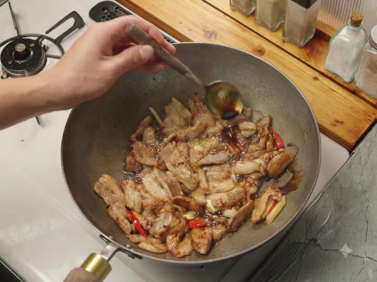Salsa di soia versata da un cucchiaio sul bordo caldo di un wok contenente carne e aromi.
