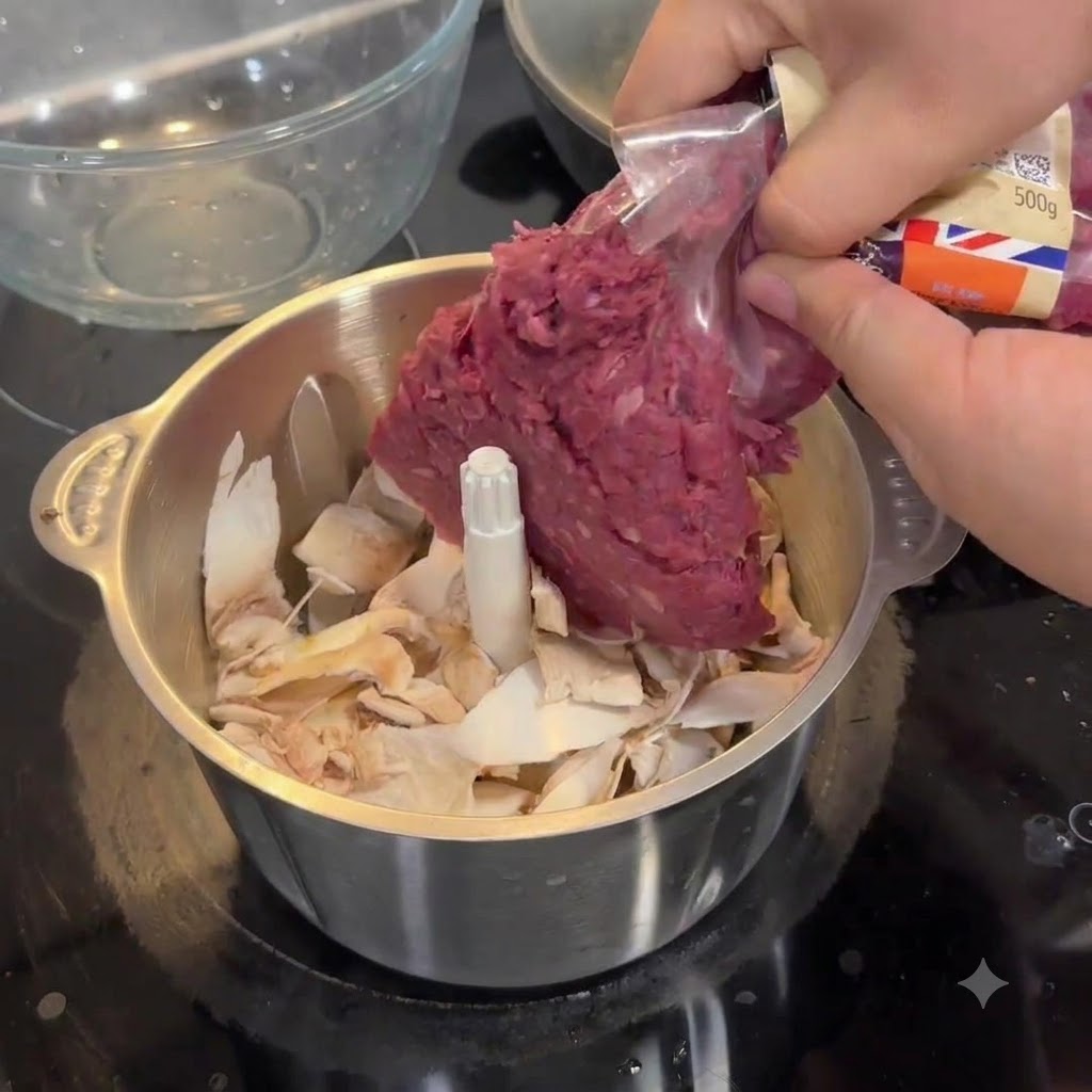 Mani che spremono carne macinata cruda da una confezione di plastica nella ciotola dacciaio di un robot da cucina piena di pezzi di funghi.