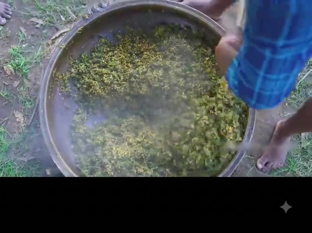 Una persona che mescola il curry di okra verde e uova finito in una grande pentola di ferro.