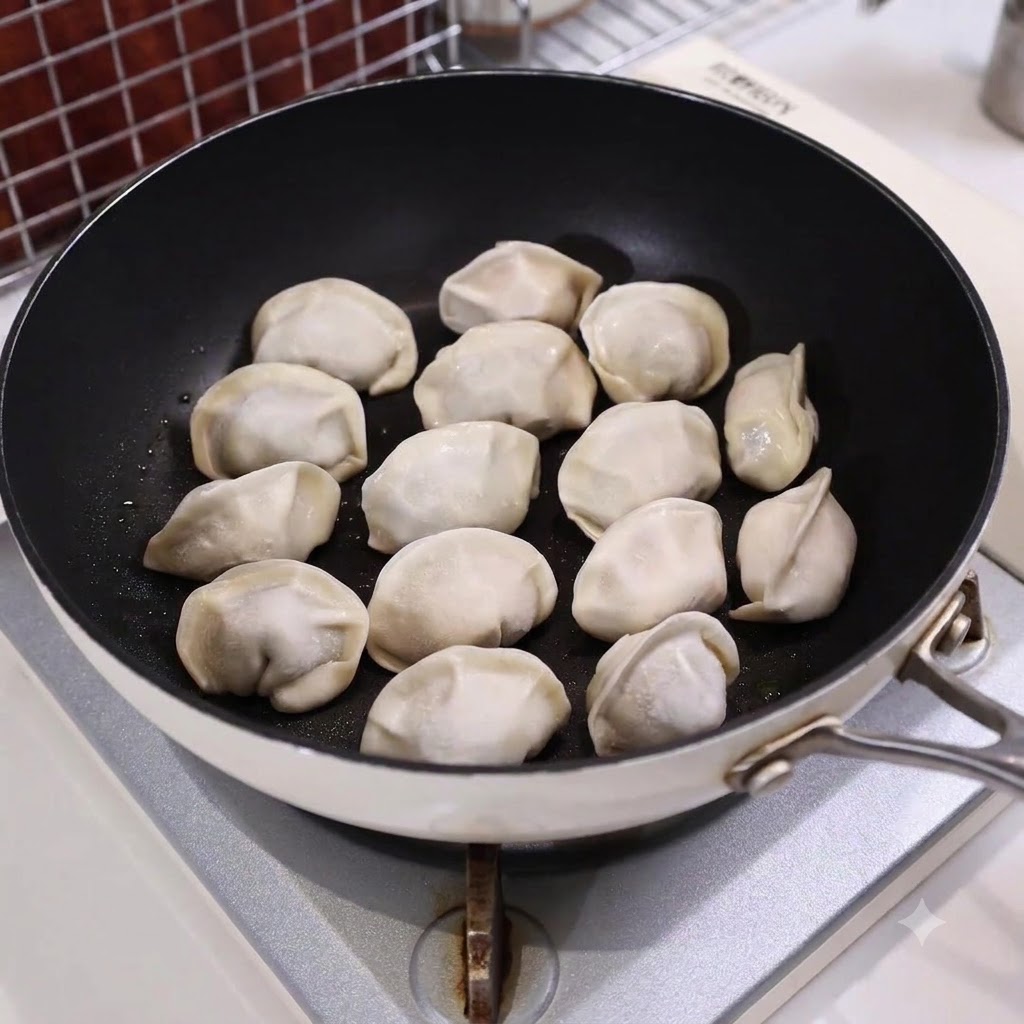 Una padella riempita di ravioli disposti e parzialmente sommersi nellacqua su un piano cottura.