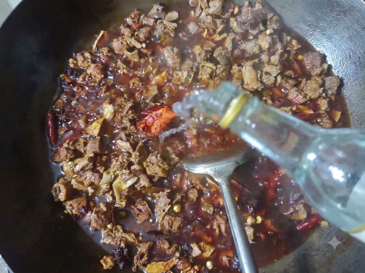 Una bottiglia che versa baijiu trasparente in un wok pieno di manzo in brasatura e spezie.