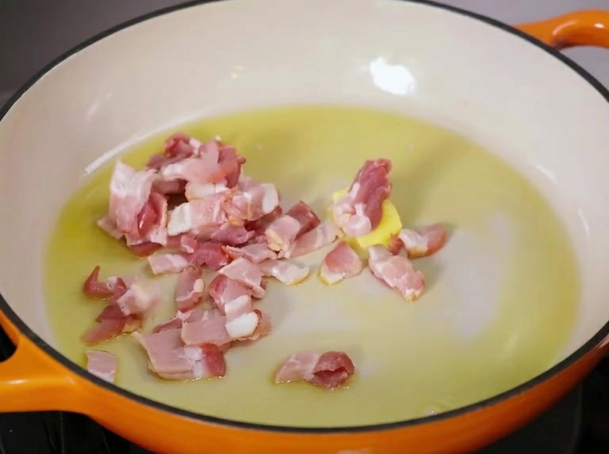 Pezzetti di pancetta che sfrigolano in padella con burro sciolto e olio doliva.