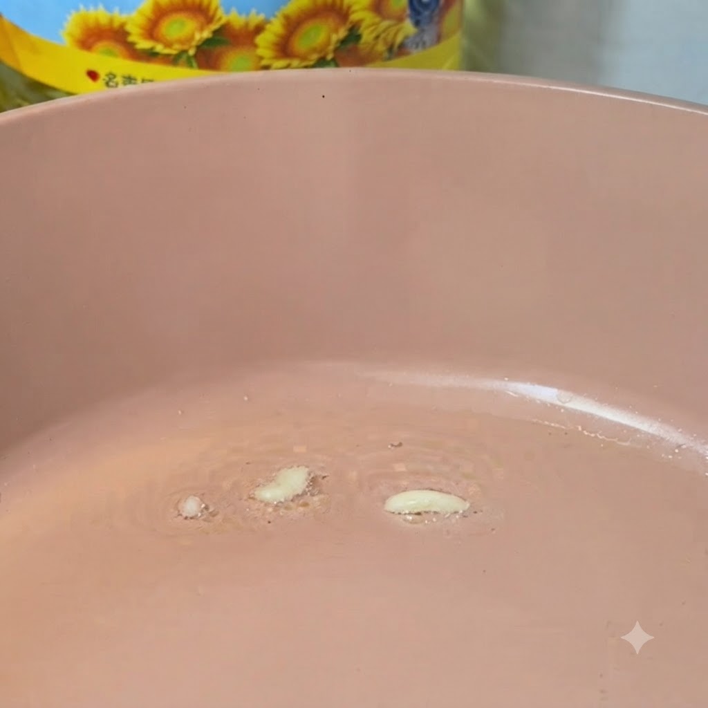 Aglio tritato che frigge in una padella rosa calda con lolio.