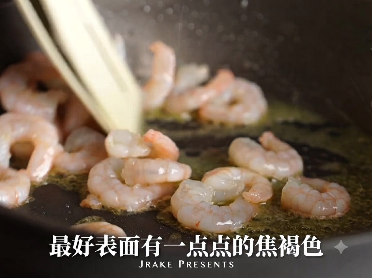 Gamberi che scottano in una padella con olio, diventando rosa e sviluppando una superficie caramellata.