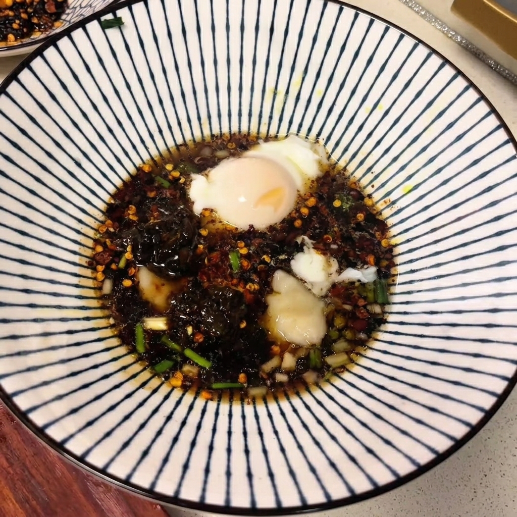 Una ciotola in ceramica piena di brodo scuro, spezie e un uovo in camicia galleggiante.