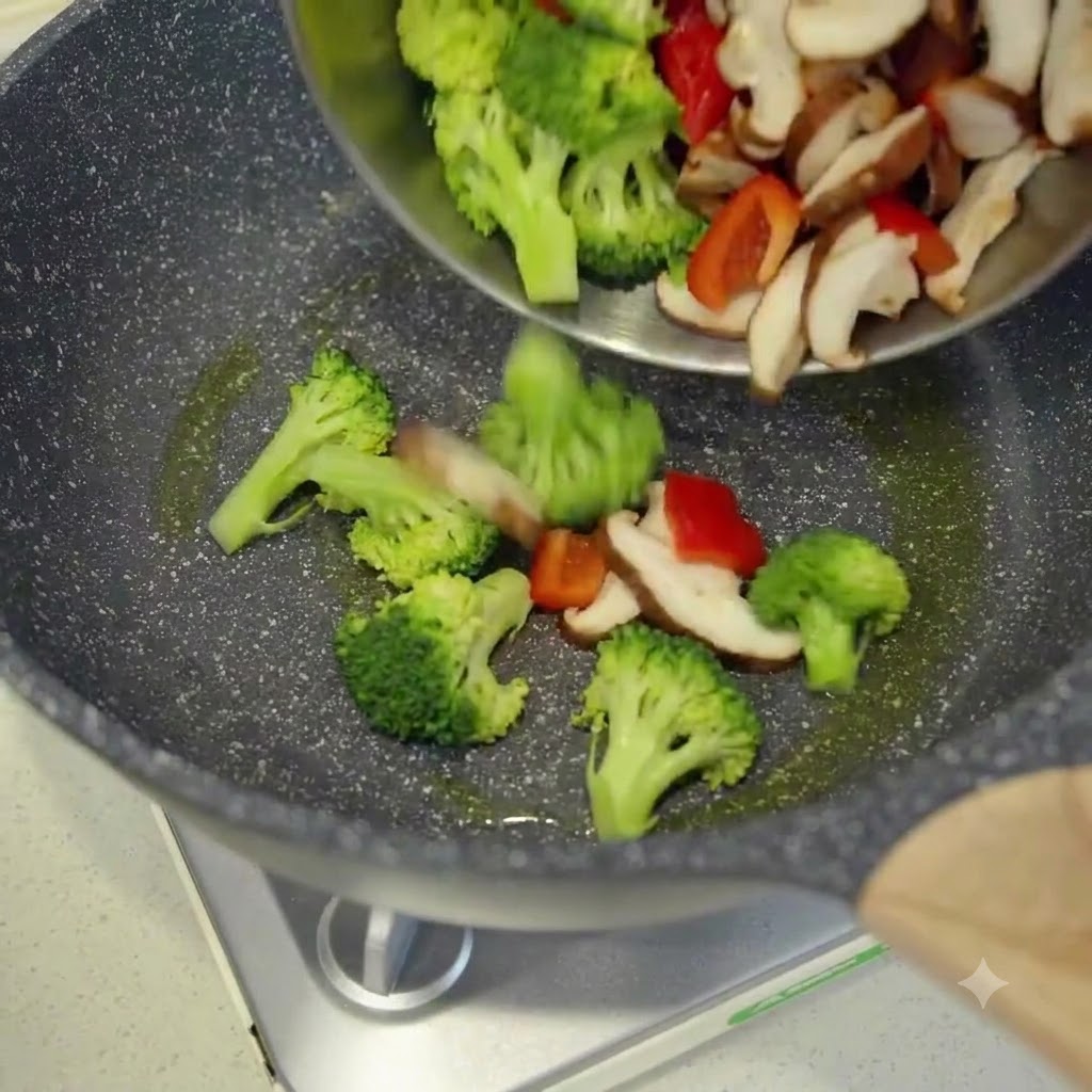 Verdure fresche affettate versate da una ciotola in un wok caldo oliato.