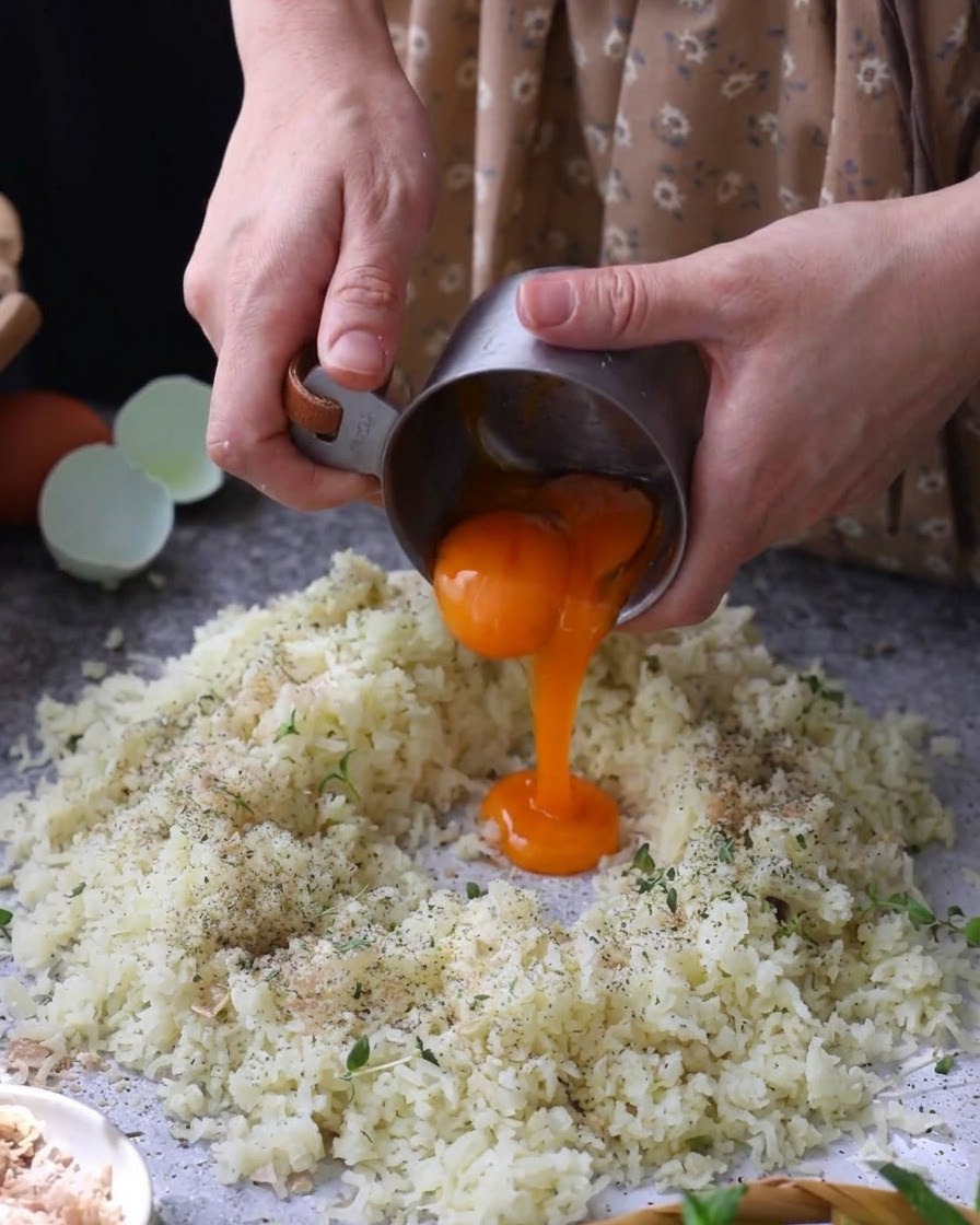 Tuorli duovo crudi versati al centro delle patate schiacciate e condite.