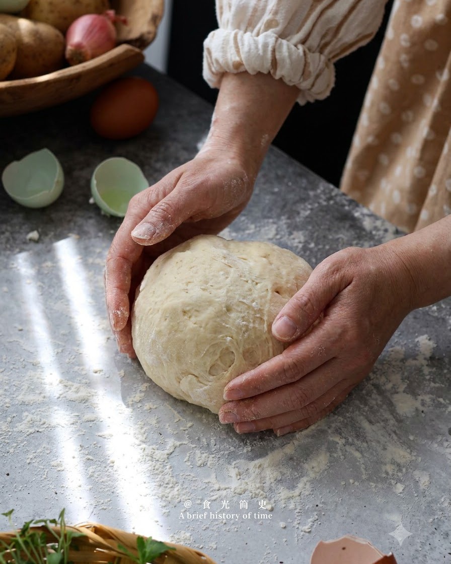 Mani che formano e impastano delicatamente limpasto degli gnocchi di patate in una palla su una superficie infarinata.