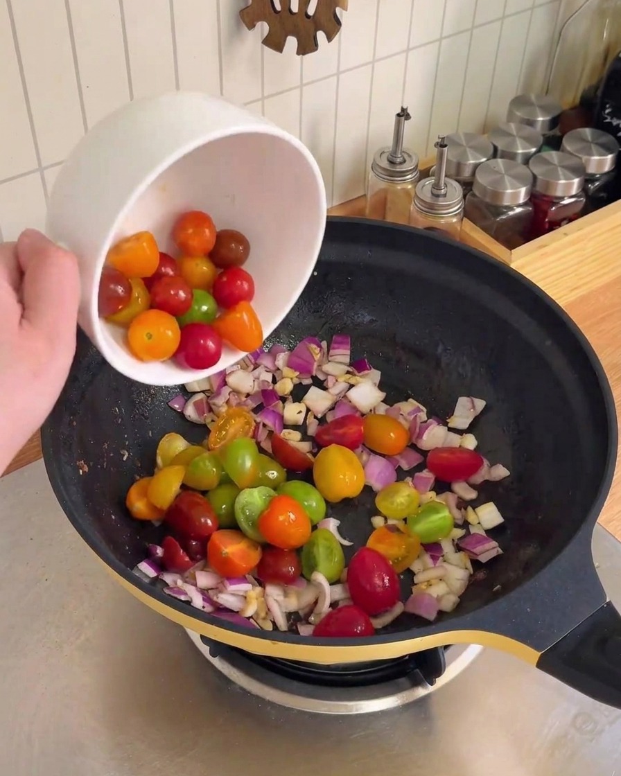 Cipolla rossa tritata e aglio saltati e soffritti in un wok nero.