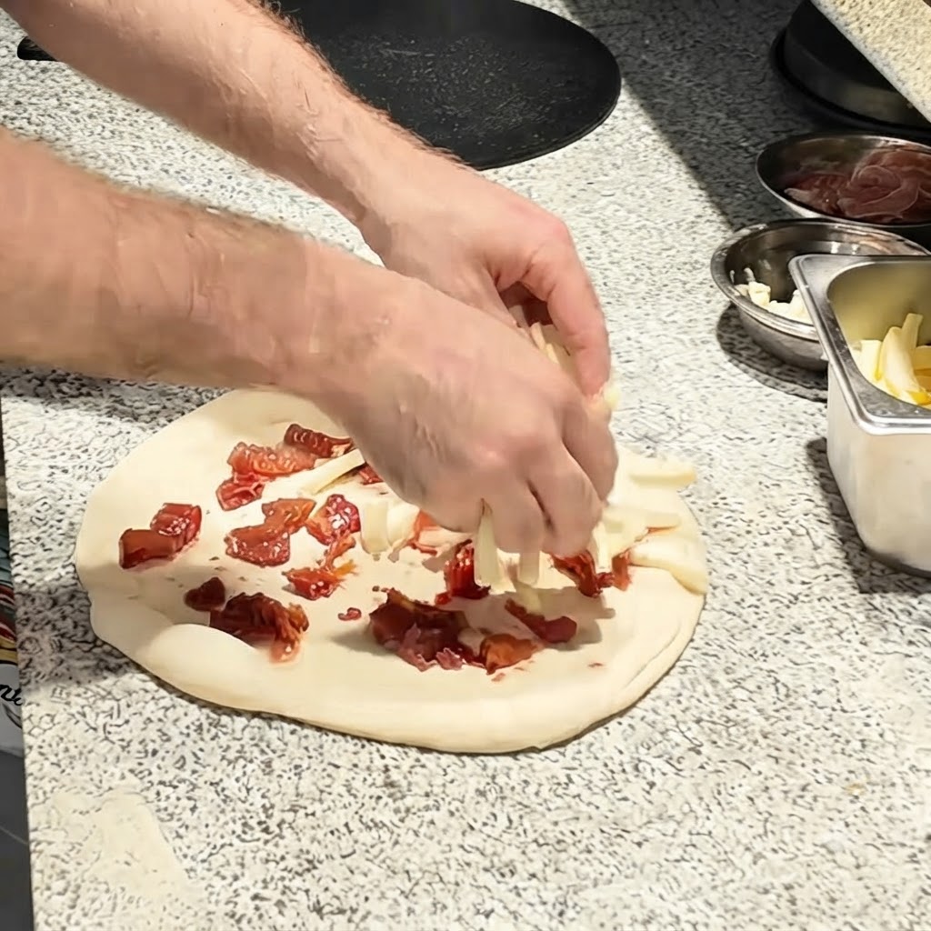 Strisce di mozzarella cosparse sopra la base di pomodoro sulla pasta per pizza.
