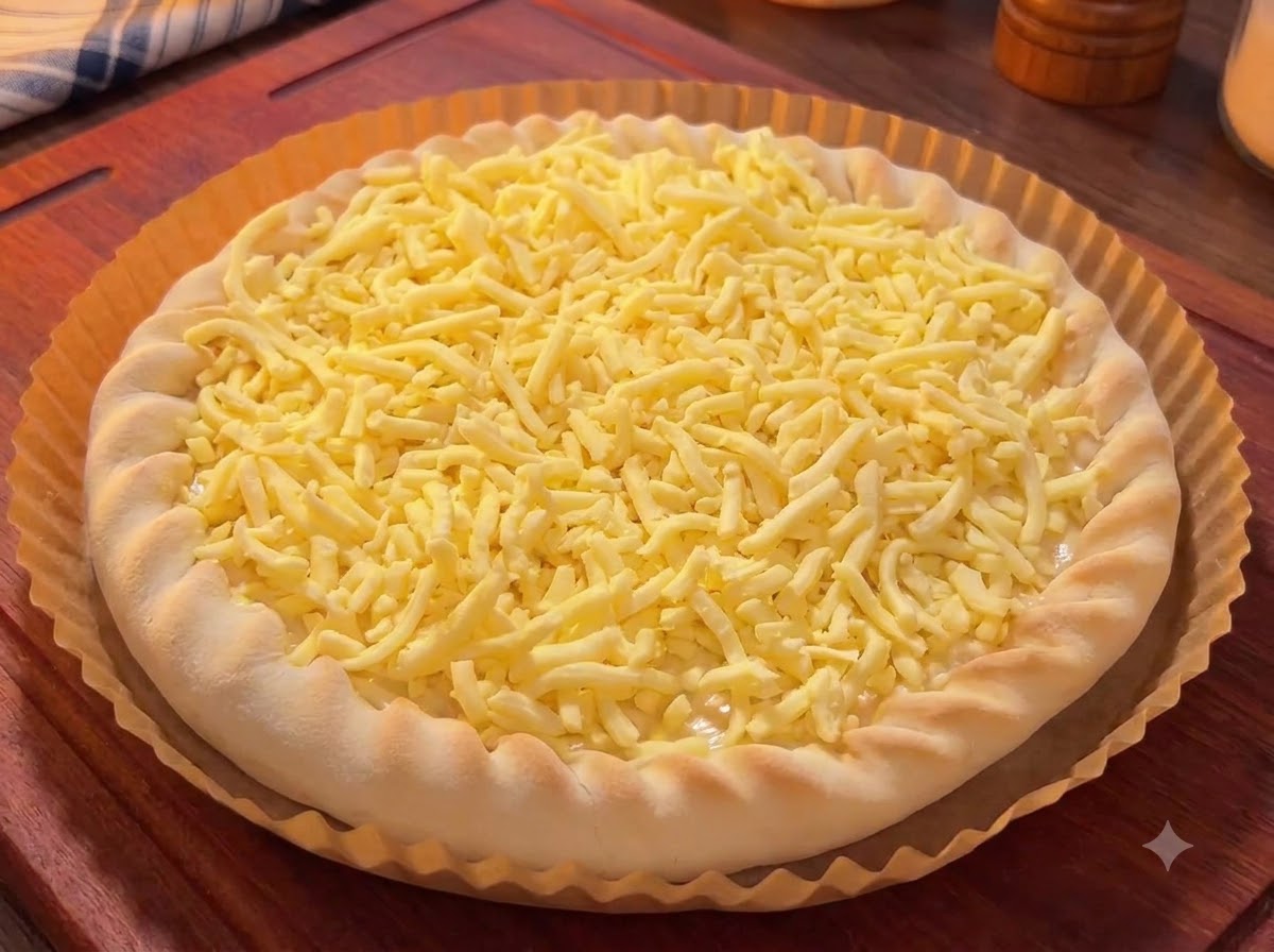 Una base per pizza ricoperta di formaggio grattugiato, sormontata da pezzi colorati di mango, pitaya e ciliegie.