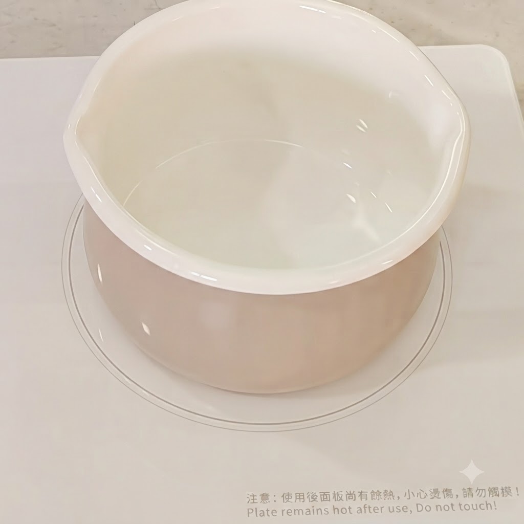 Acqua versata in una pentola da cucina bianca su un piano cottura.