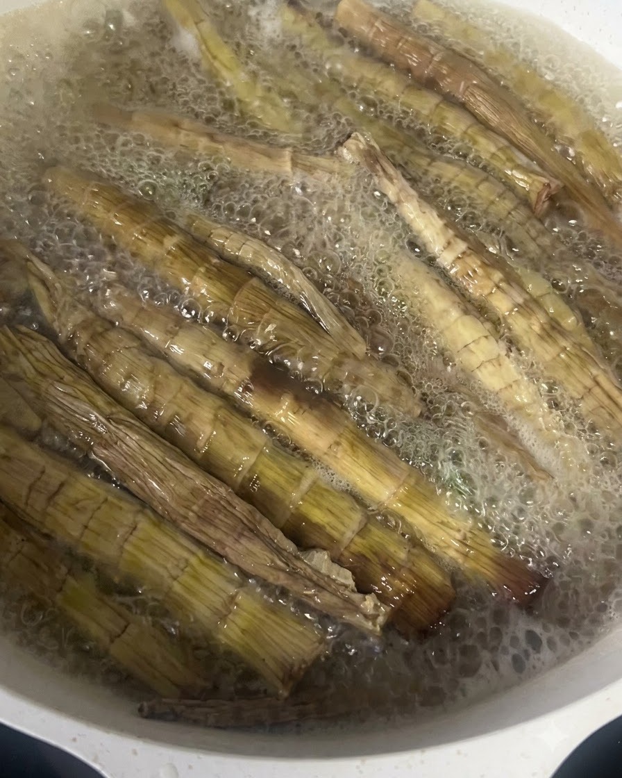 Germogli di bambù essiccati che bollono vivacemente in una pentola di acqua calda.