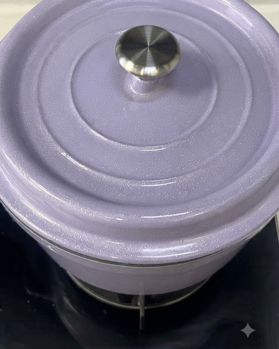 Un primo piano di una pentola in ghisa smaltata viola chiaro con il suo coperchio appoggiato sopra.