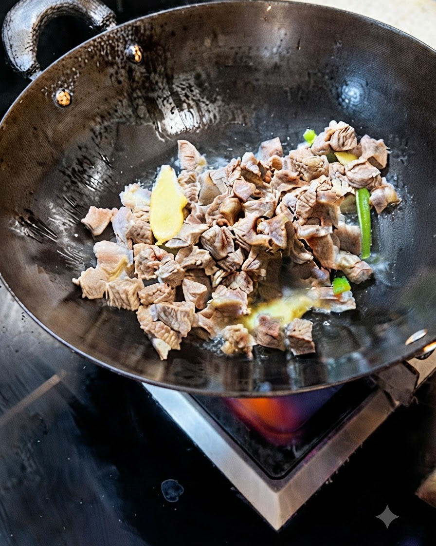 Cubetti di manzo sbollentati che saltano in un wok con fette di zenzero e cipollotto.