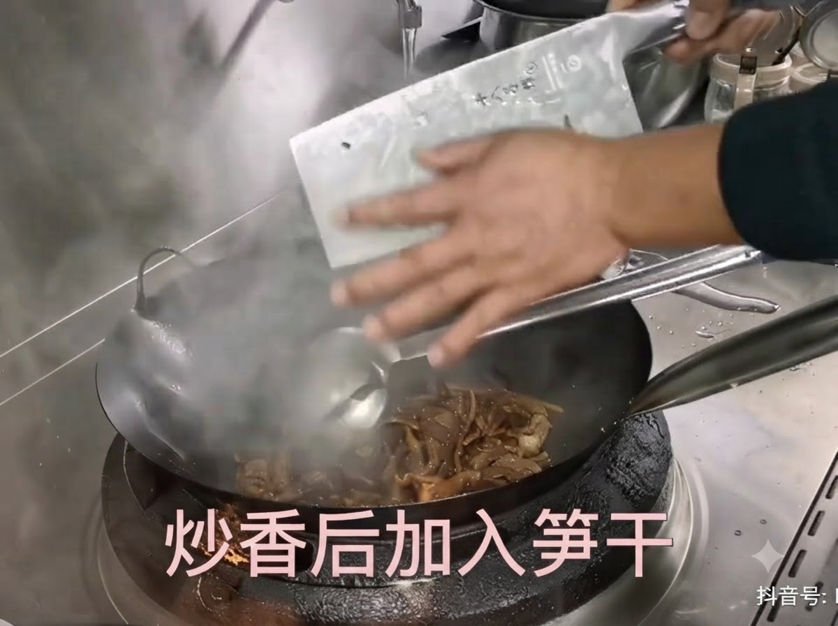 Germogli di bambù essiccati preparati raschiati da una mannaia in un wok caldo con maiale saltato.