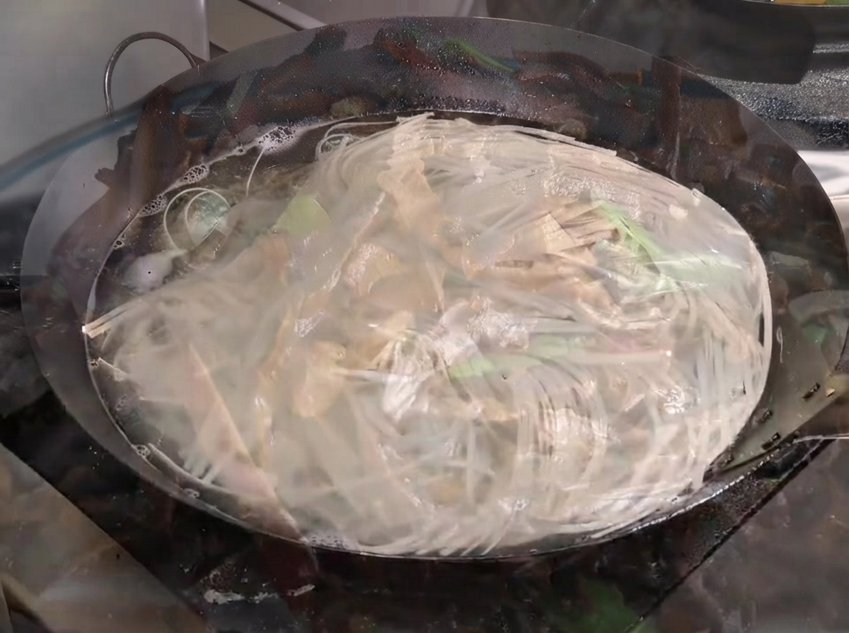 Noodles che bollono vigorosamente in un grande wok pieno dacqua.