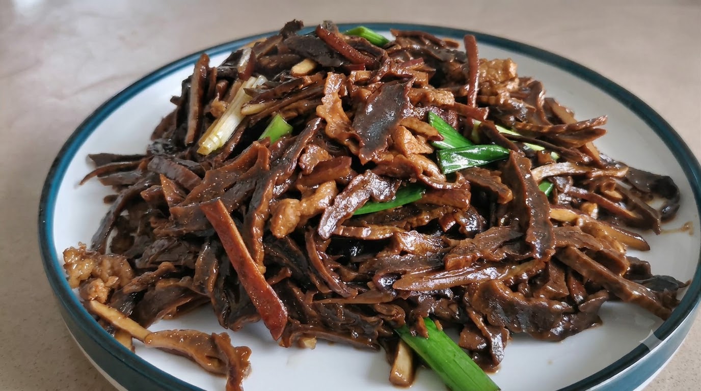 Un piatto di germogli di bambù essiccati e maiale sminuzzati saltati e saporiti, guarniti con germogli di aglio verde