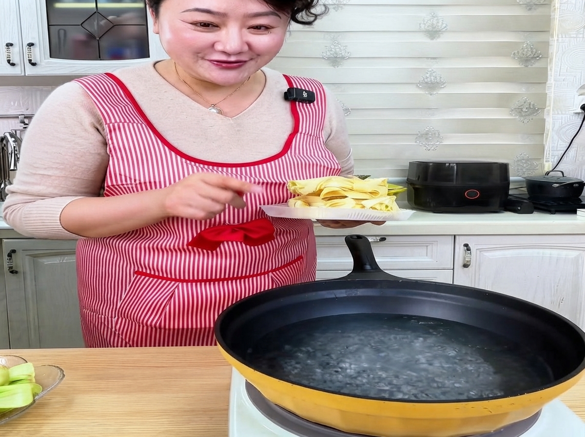 Noodles larghi di grano essiccati immersi in una pentola di acqua bollente.