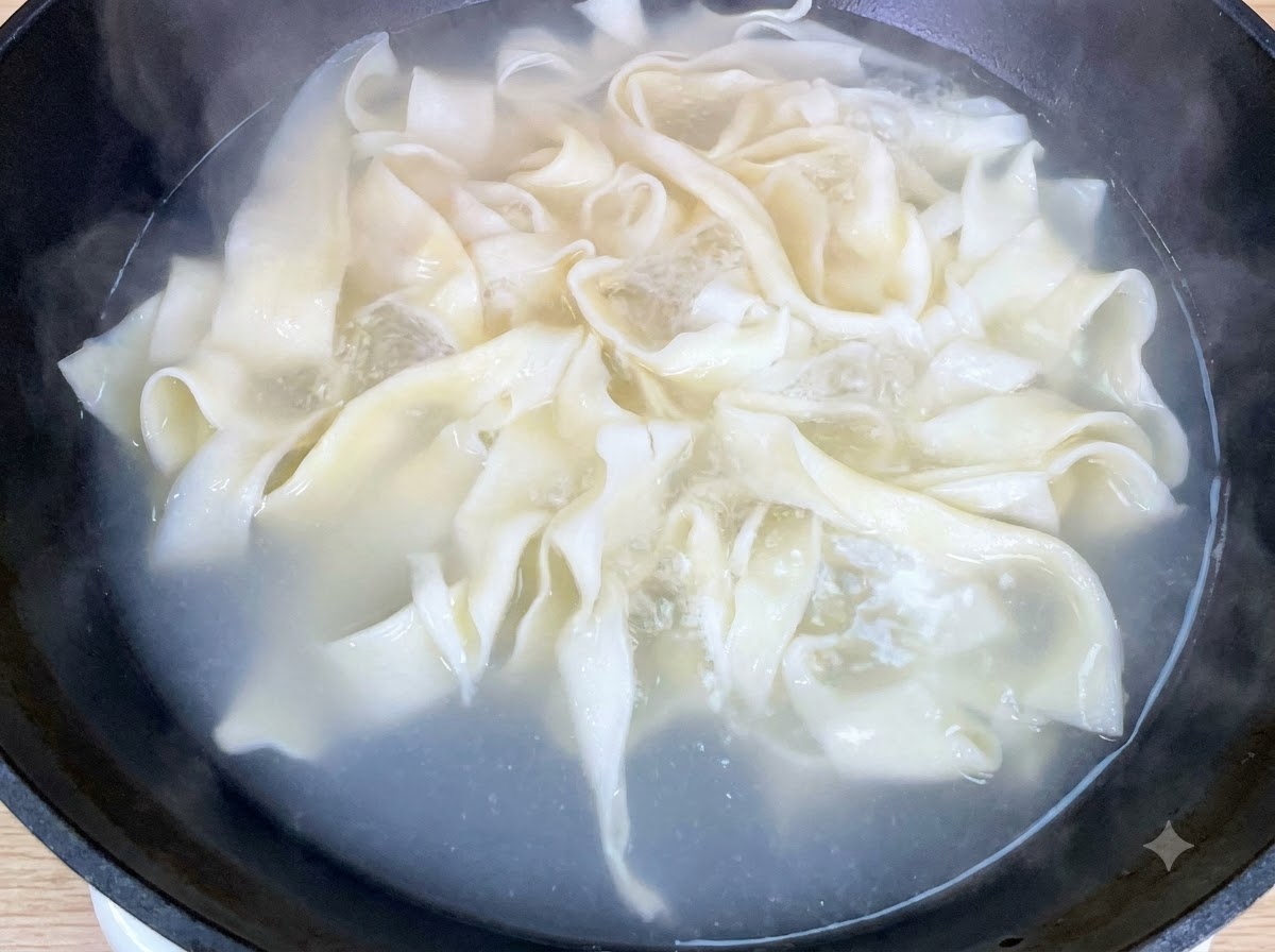 Baby bok choy fresco che cuoce insieme ai noodles larghi in padella.