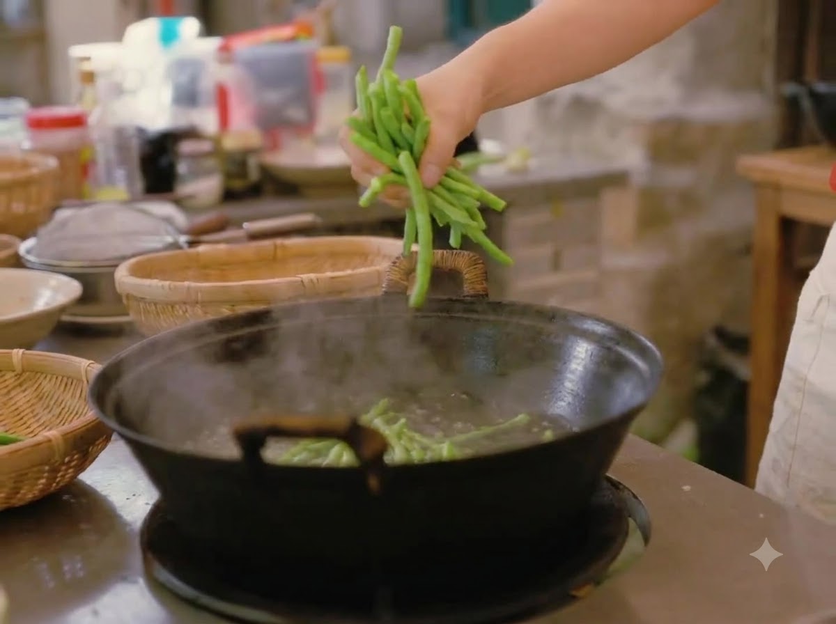 Una mano tuffa una manciata di fagiolini freschi in un grande wok di acqua bollente.