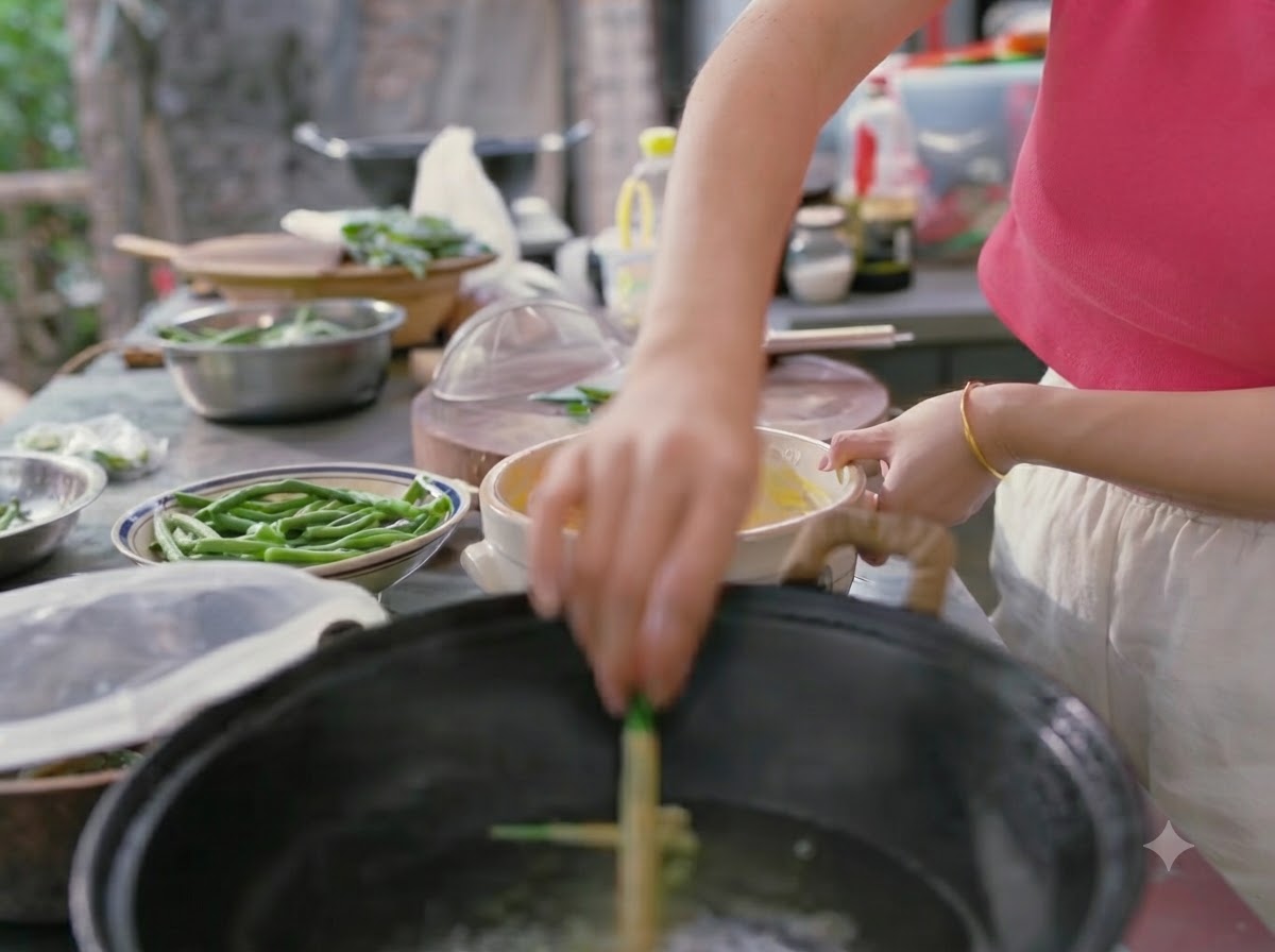 Una mano immerge i fagiolini ricoperti di pastella in un wok di acqua bollente.