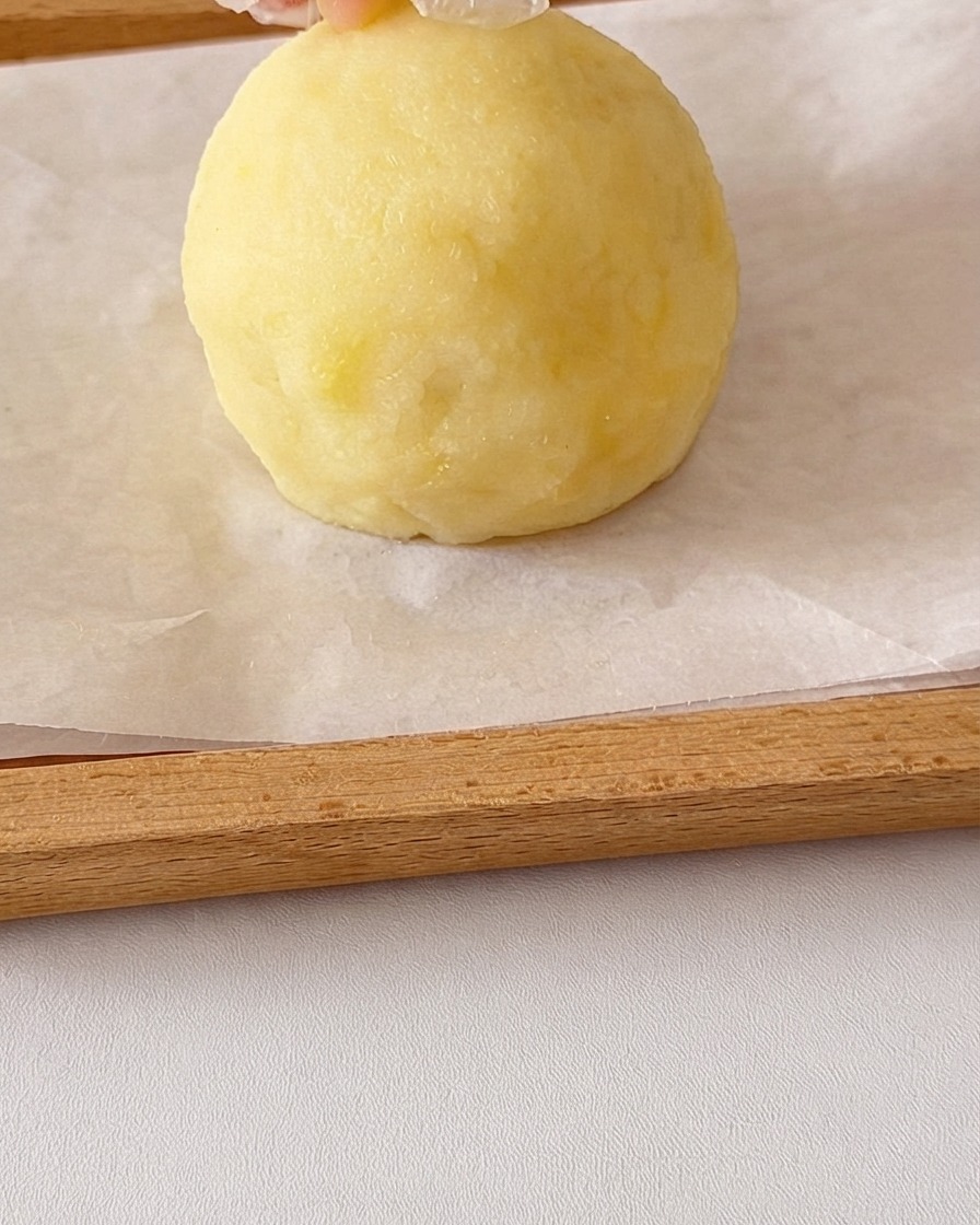Una palla rotonda di purè di patate modellata a mano con piccoli pezzi di patata aggiunti sopra per le orecchie.
