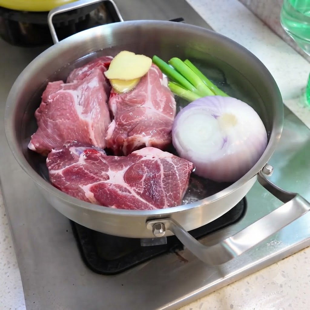Acqua versata in una padella riempita con maiale, cipolla, zenzero, cipollotti e spezie.