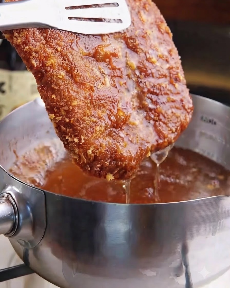 Una cotoletta fritta dorata e croccante sollevata dallolio bollente con le pinze.