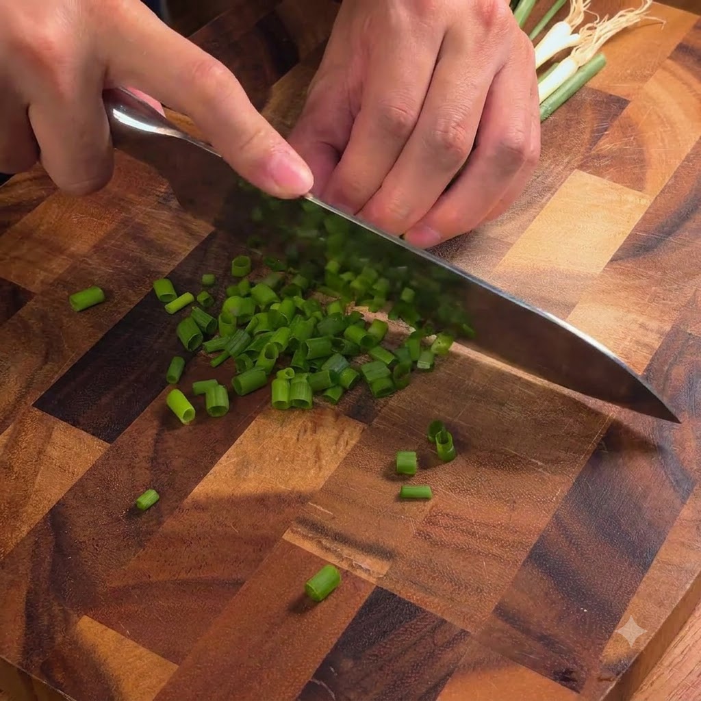 Il coltello di uno chef che affetta cipollotti verdi freschi in pezzi sottili su un tagliere di legno.