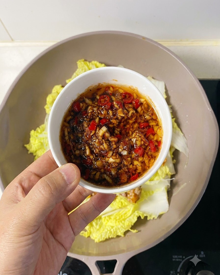 Salsa saporita di aglio e peperoncino versata generosamente sulla polpa di capasanta disposta.