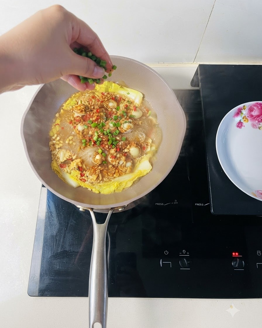 Cipollotti tritati freschi cosparsi su una padella di capesante cotte e noodle vermicelli.