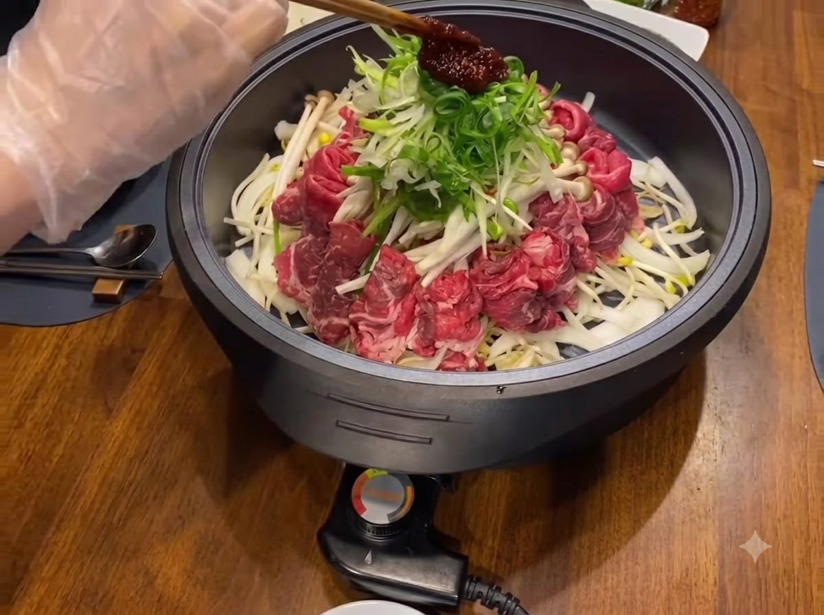 Una cucchiaiata di salsa di condimento rosso scuro posta sopra cipolle verdi sminuzzate e carni in una padella nera.