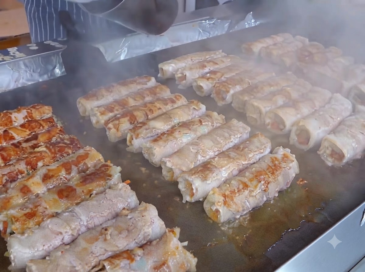 Una fetta di formaggio giallo posizionata sopra lo strato di kimchi sopra gli involtini di carne preparati.