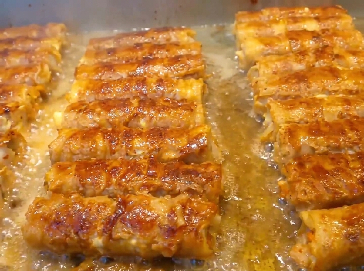 Mani che arrotolano saldamente la pancetta di maiale a strati e i ripieni in una stretta forma cilindrica.