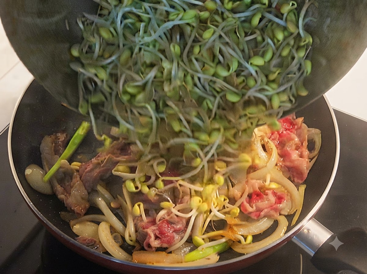 Germogli di soia gialli freschi versati da una ciotola in una padella contenente manzo e cipolle parzialmente cotti.